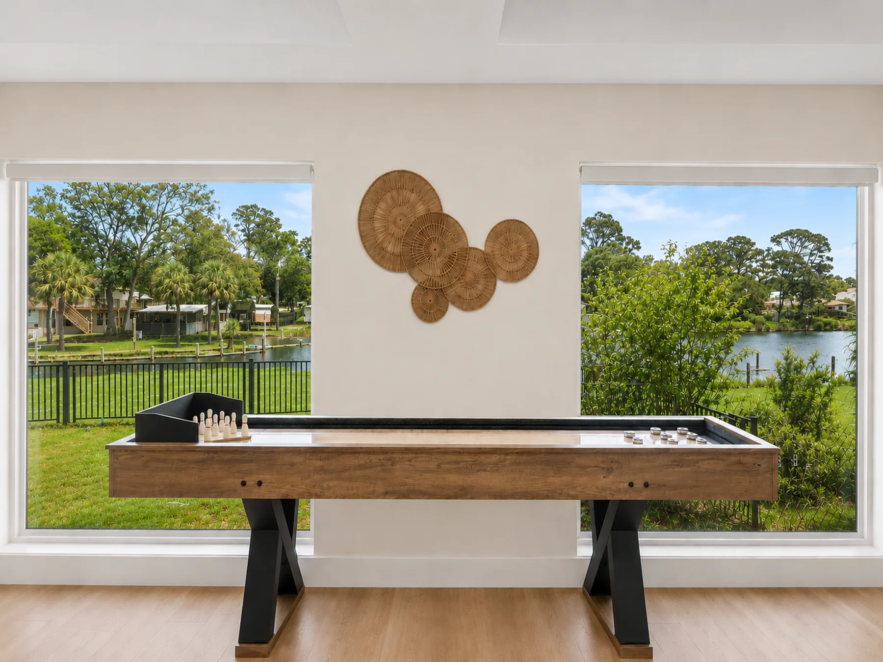 Una sala de juegos con una mesa de billar entre ventanas con vistas a vegetación y agua.