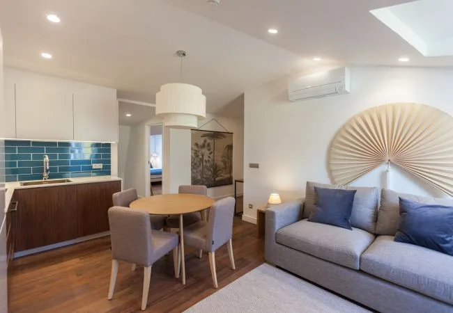 A bright living and dining area with a sofa, table, and kitchenette.