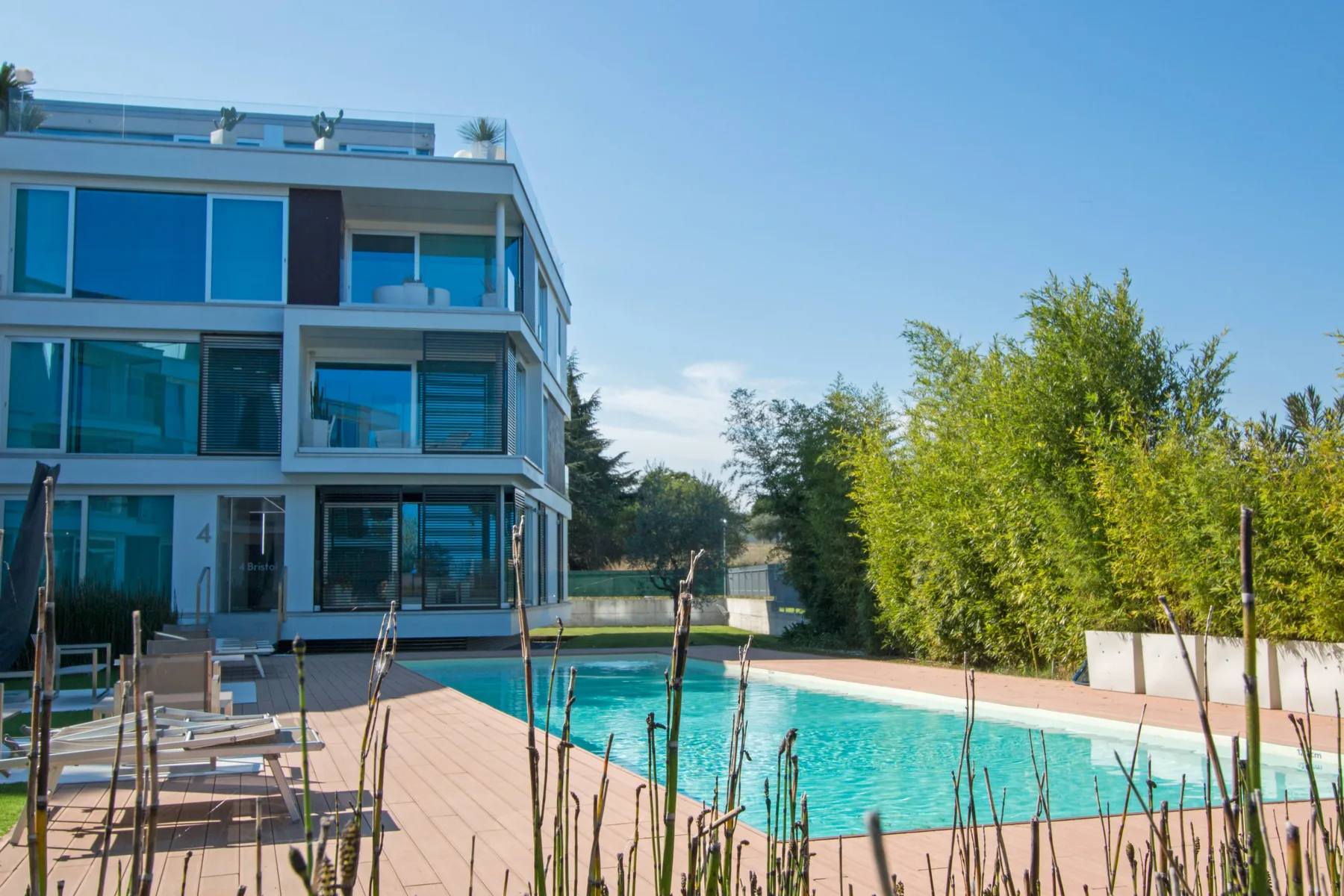 Zona común: Piscina al aire libre junto a un edificio moderno con fachada de vidrio.