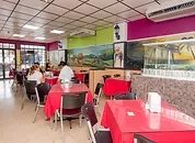Representative hotel space: A dining area has red tablecloths, chairs, and a long counter along the wall.