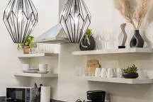 A bright kitchen with open shelves displaying dishes and small plants.