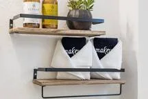 A wall shelf displays bottles and a potted plant above hanging fabric bags.