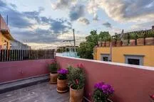 A rooftop terrace overlooks nearby buildings beneath a cloudy sky.