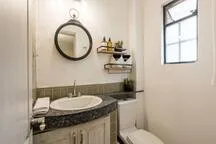 A bathroom vanity with a round mirror and wall-mounted shelves.