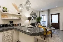 A kitchen with a curved counter, open shelves, and a dining area.