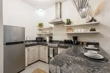 A kitchen with pale cabinets, a range, and a dark stone countertop.