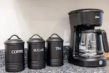 A kitchen counter with a drip coffee maker and labeled canisters.