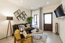 A living room with seating, a coffee table, and a wall-mounted television.