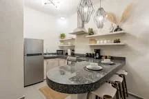 A modern kitchen with a curved island, bar seating, and pendant lights.