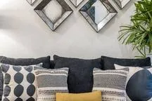 Living room seating with patterned cushions and framed wall art.