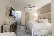 A bright bedroom with a bed, a ceiling fan, and a patterned rug.