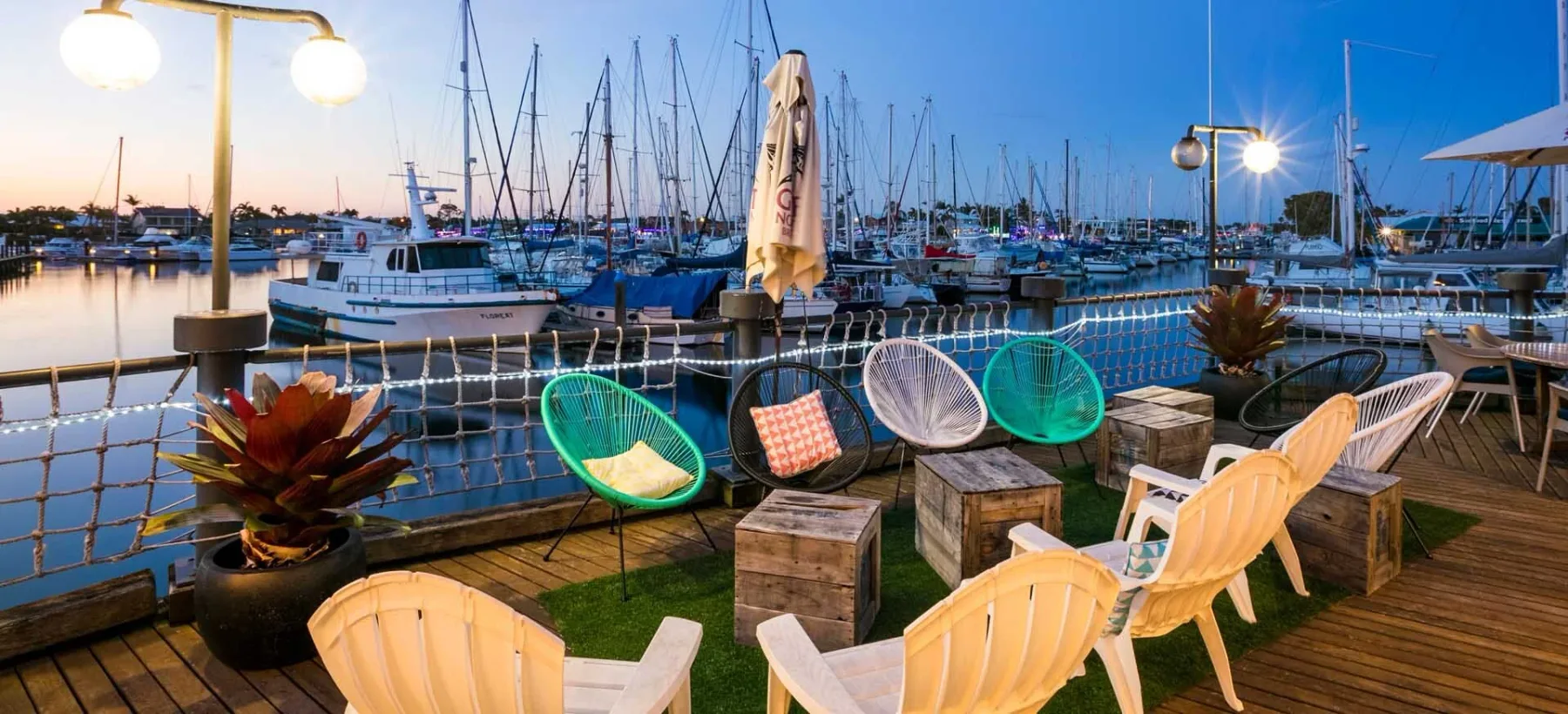 Espacio representativo del hotel: Asientos al aire libre junto al agua ofrecen vistas de una marina con veleros.