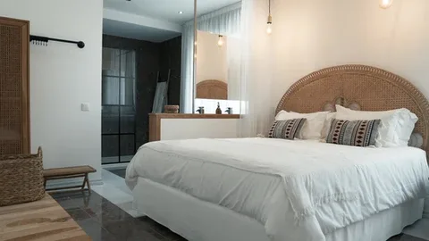 Espacio representativo del hotel: Un dormitorio luminoso con una cama grande y cabecero tejido.