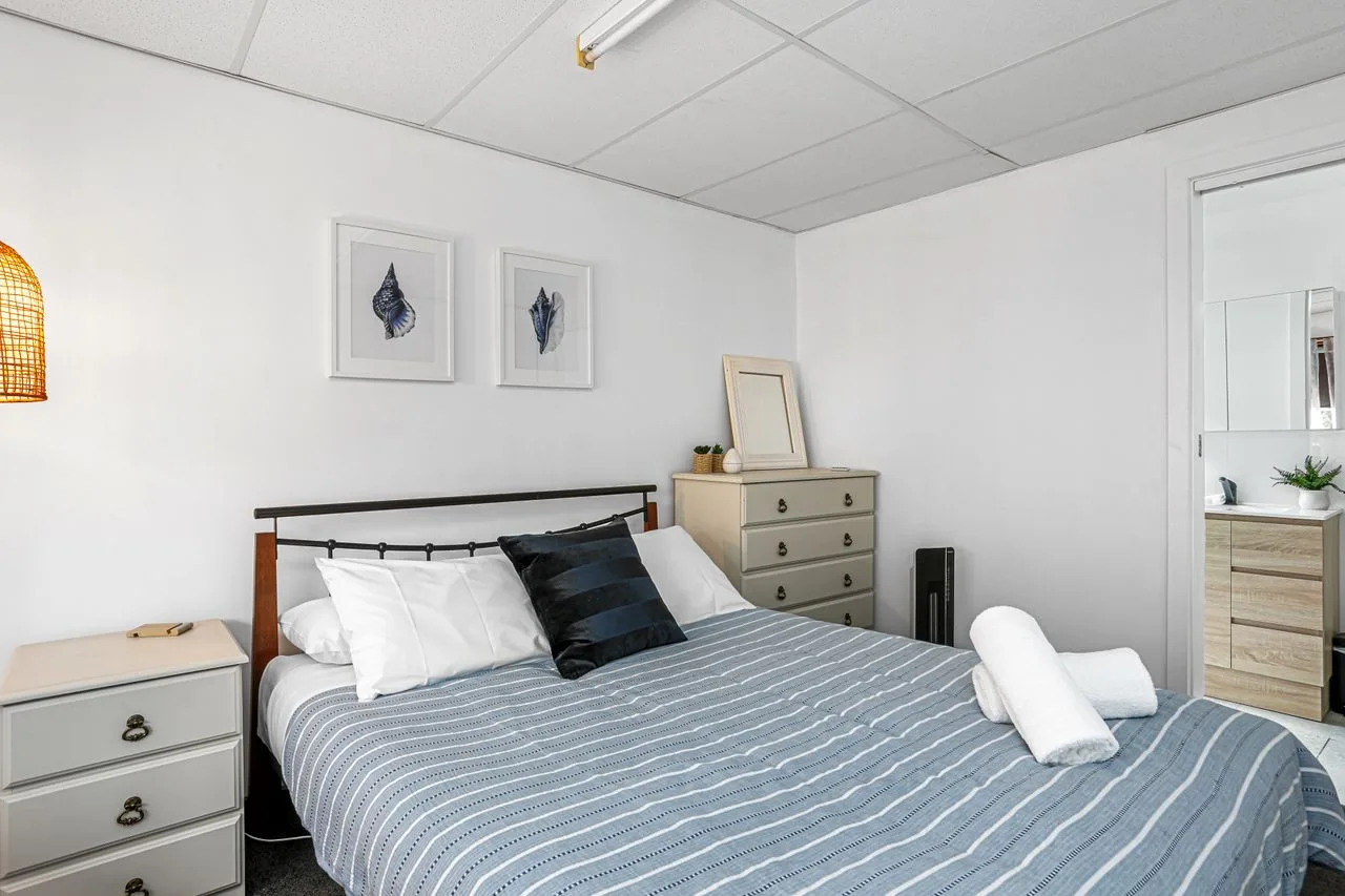 Un dormitorio con una cama tendida y dos cuadros en la pared.