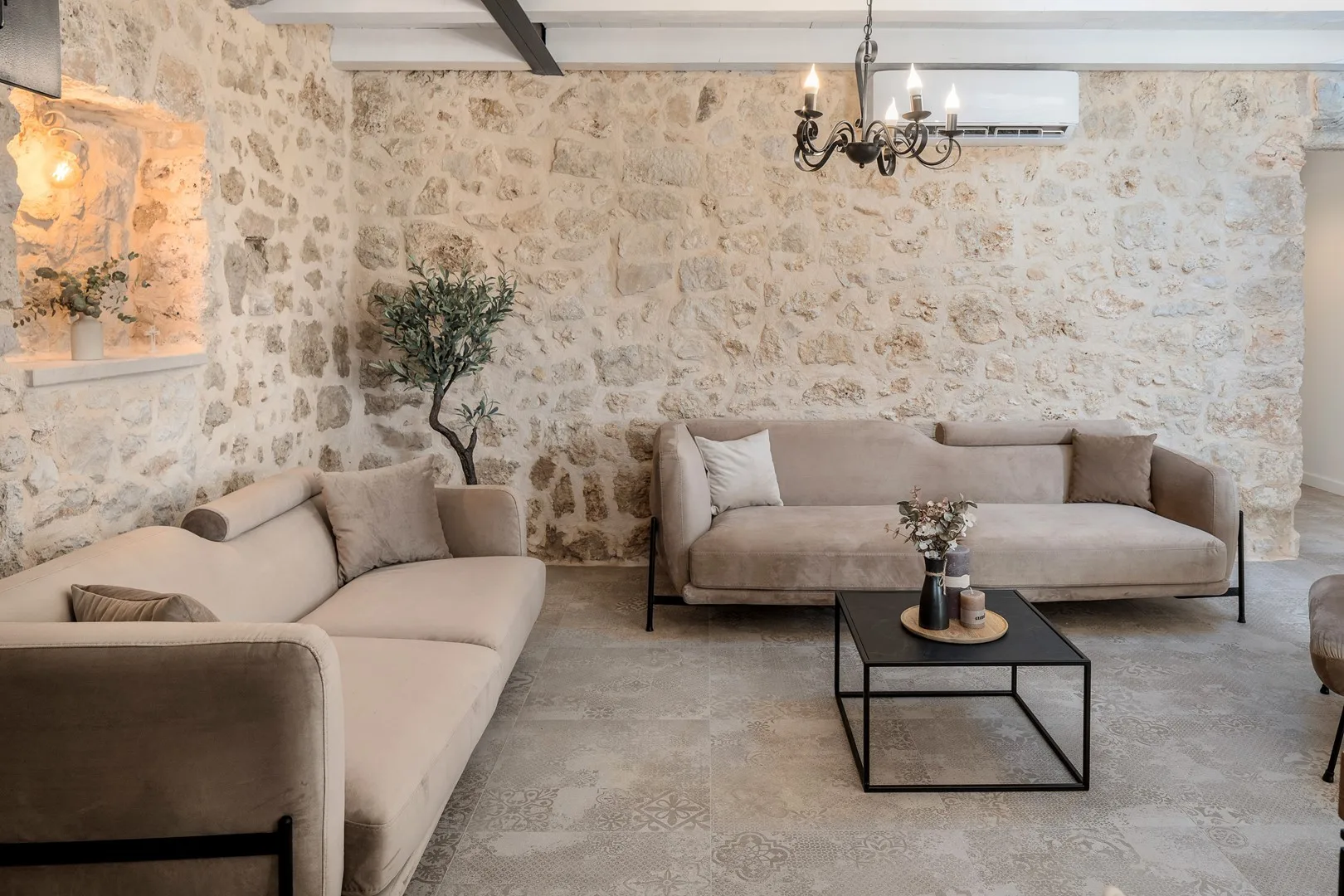 Una sala de estar con asientos claros y una mesa de centro junto a paredes de piedra.