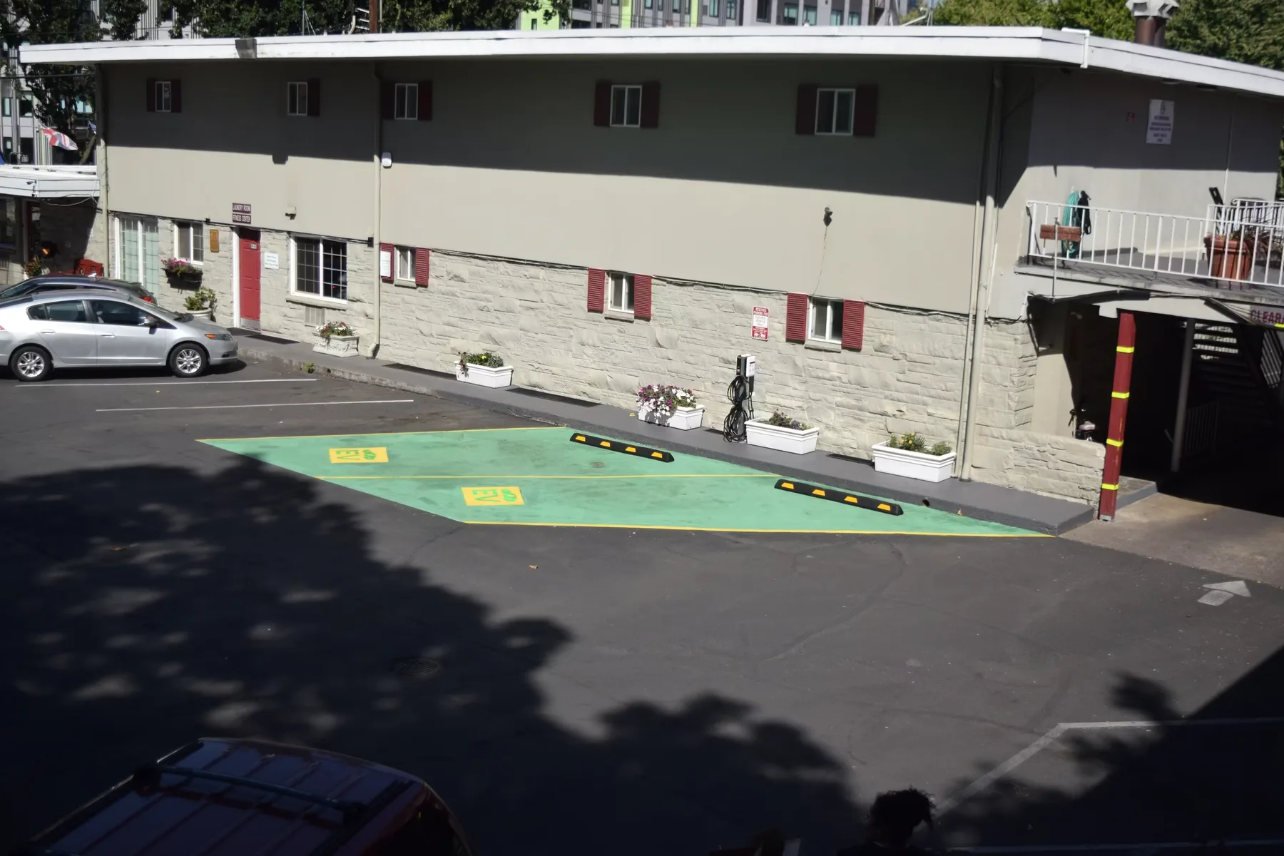 Representative hotel space: A parking area beside a low-rise building, with a green painted section.