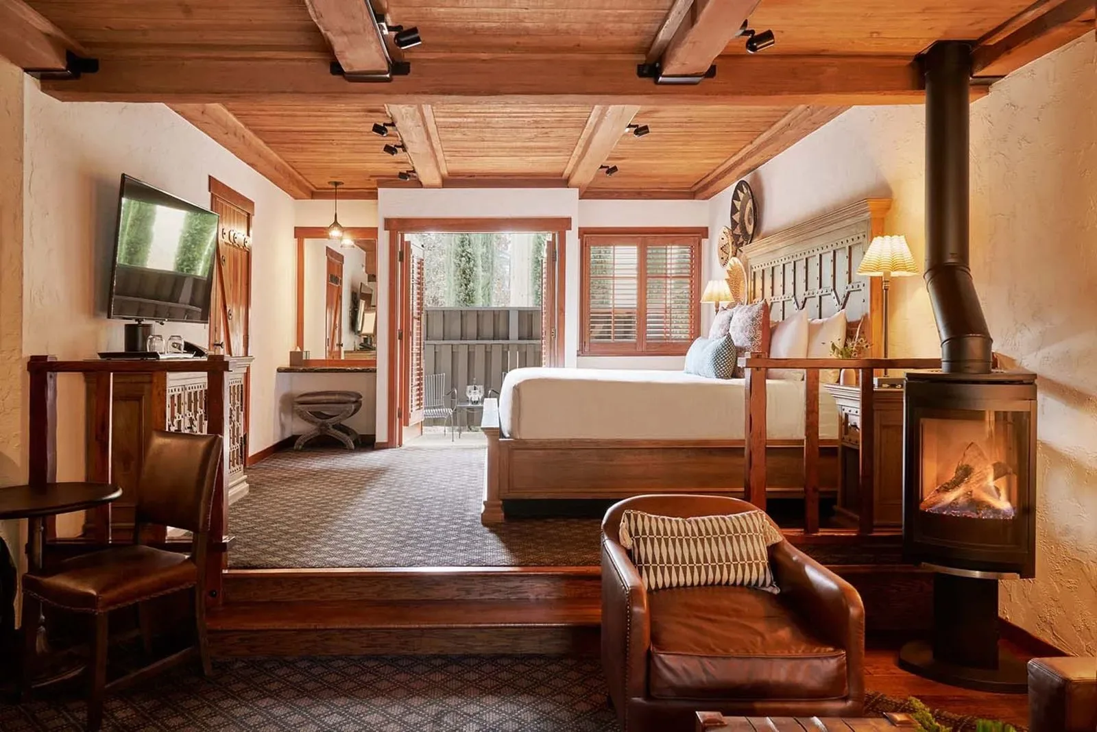 Representative hotel space: A bedroom with a raised bed, wood ceiling, and a fireplace.