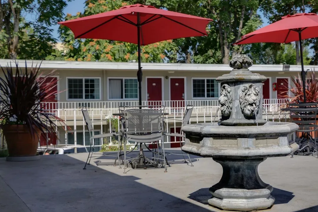 Representative hotel space: An outdoor patio with red umbrellas, seating, and a decorative fountain.