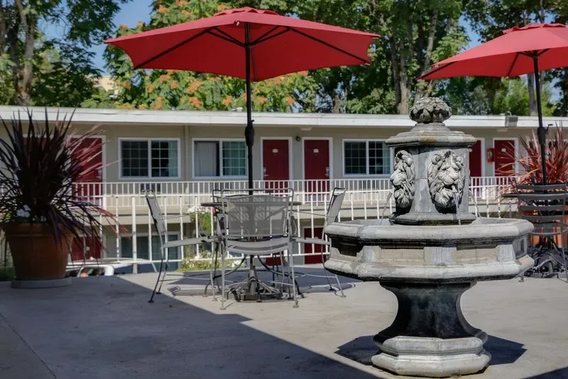 Representative hotel space: An outdoor hotel patio has seating, red umbrellas, and a decorative fountain.