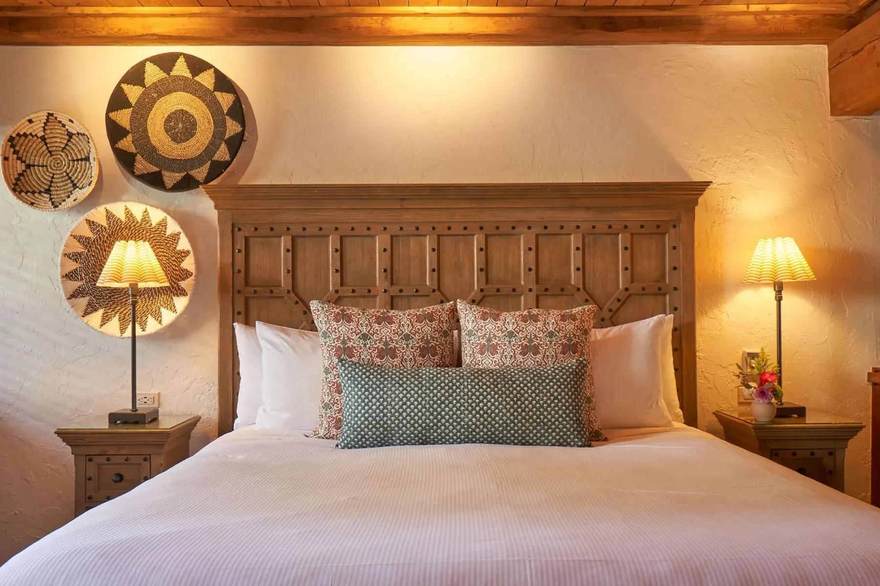 Representative hotel space: A bedroom with a wooden headboard and decorative woven wall hangings.