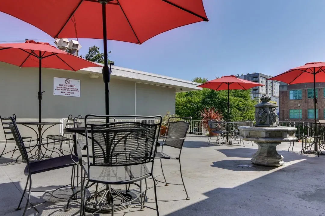 Representative hotel space: A sunny outdoor patio with seating, red umbrellas, and a fountain.