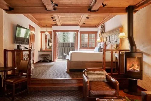 Representative hotel space: A bedroom with a raised bed, wooden ceiling, and lit fireplace.