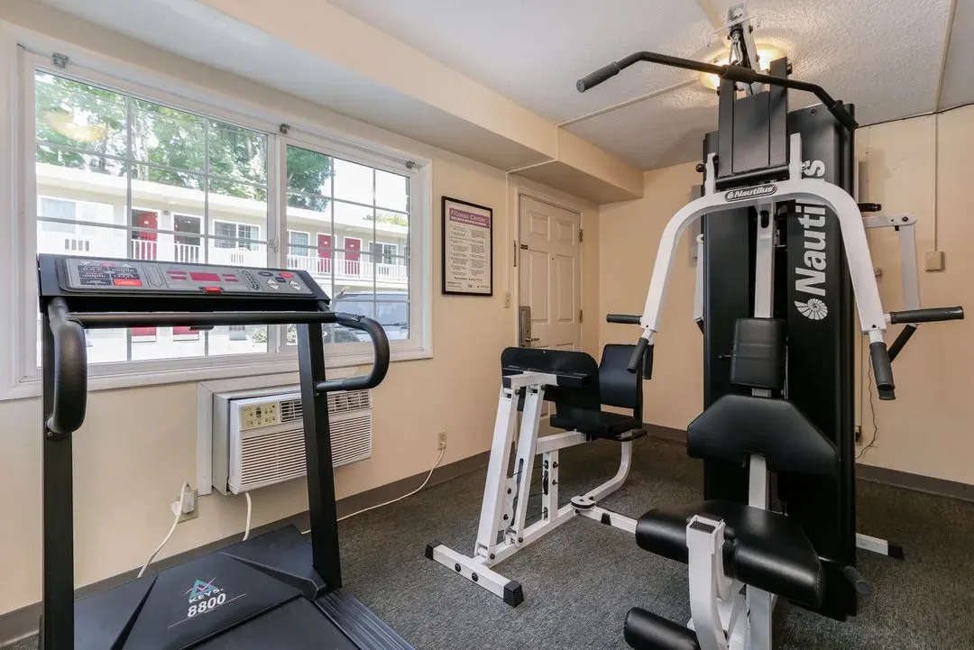 Representative hotel space: A small fitness room with exercise equipment beside large windows.