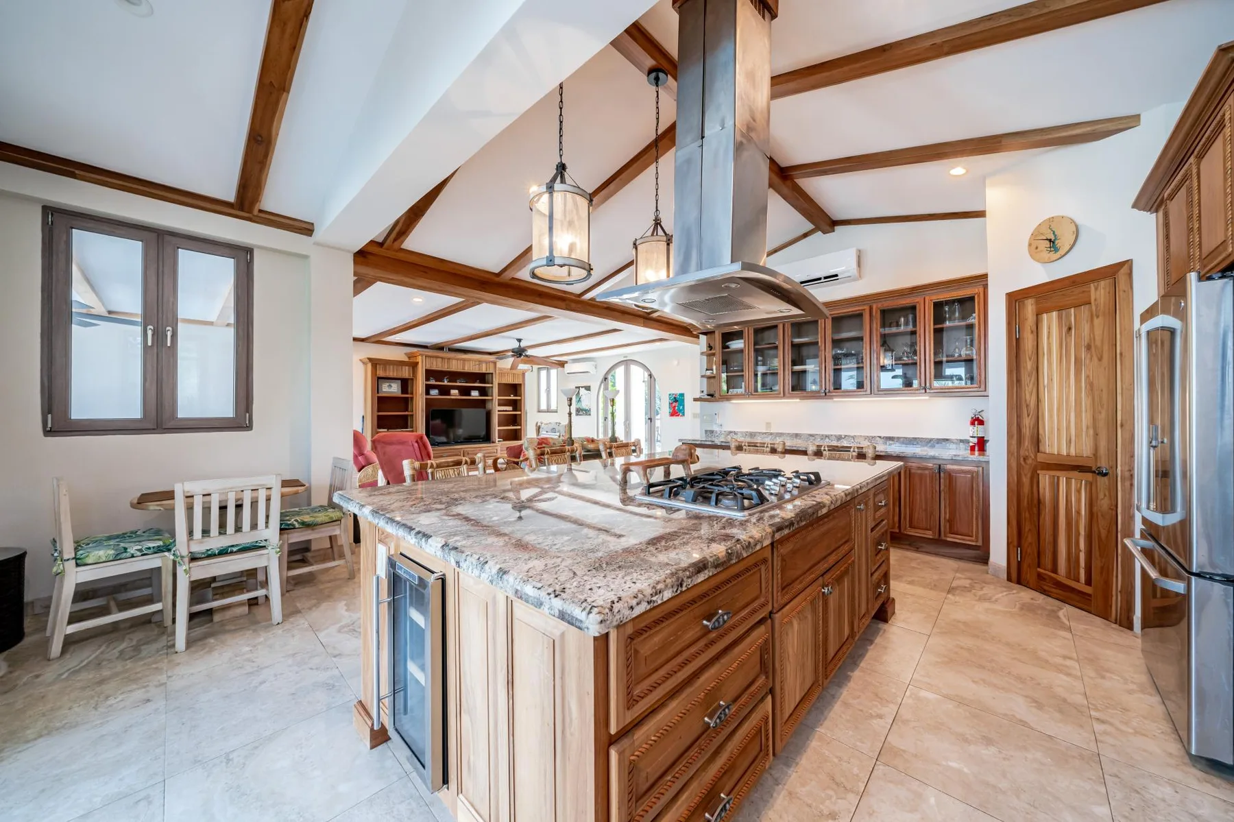 A spacious kitchen with a large central island, wooden cabinets, and a dining area.