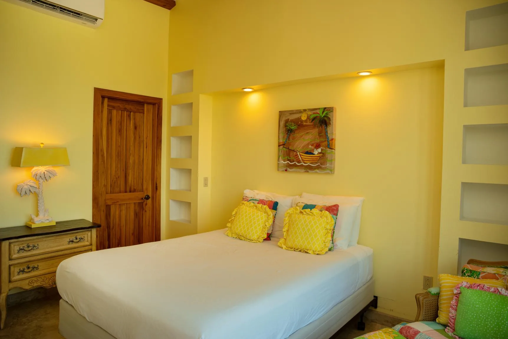 A bedroom with a bed, colorful pillows, and a wooden door.