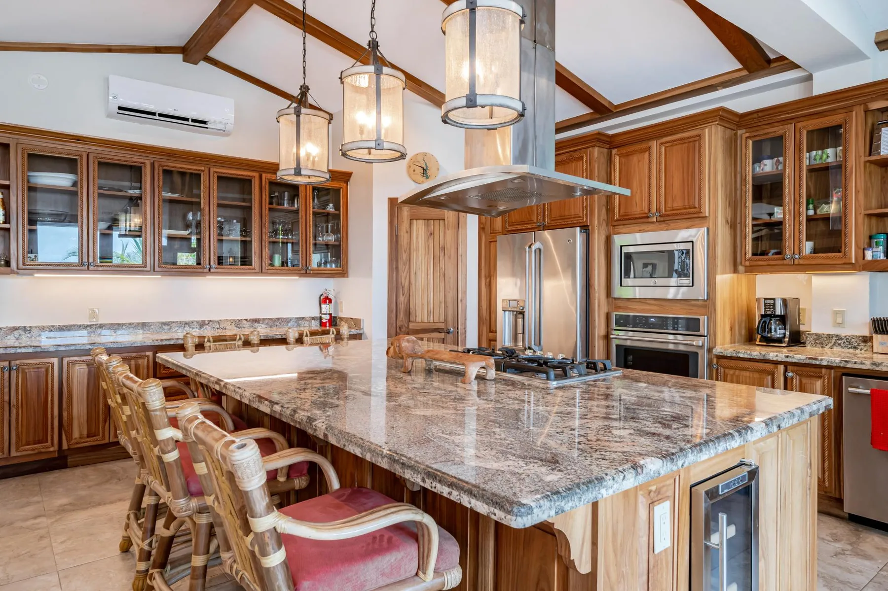 A spacious kitchen with a large island, wooden cabinets, and pendant lights.