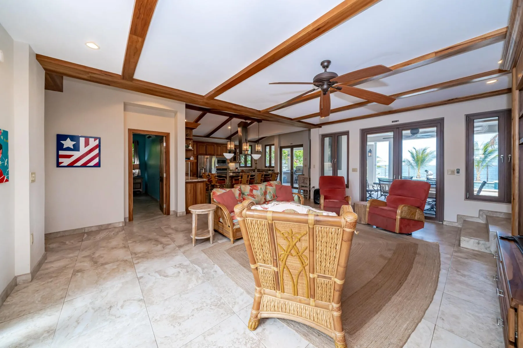 A spacious living room with wicker seating, a rug, and a ceiling fan.