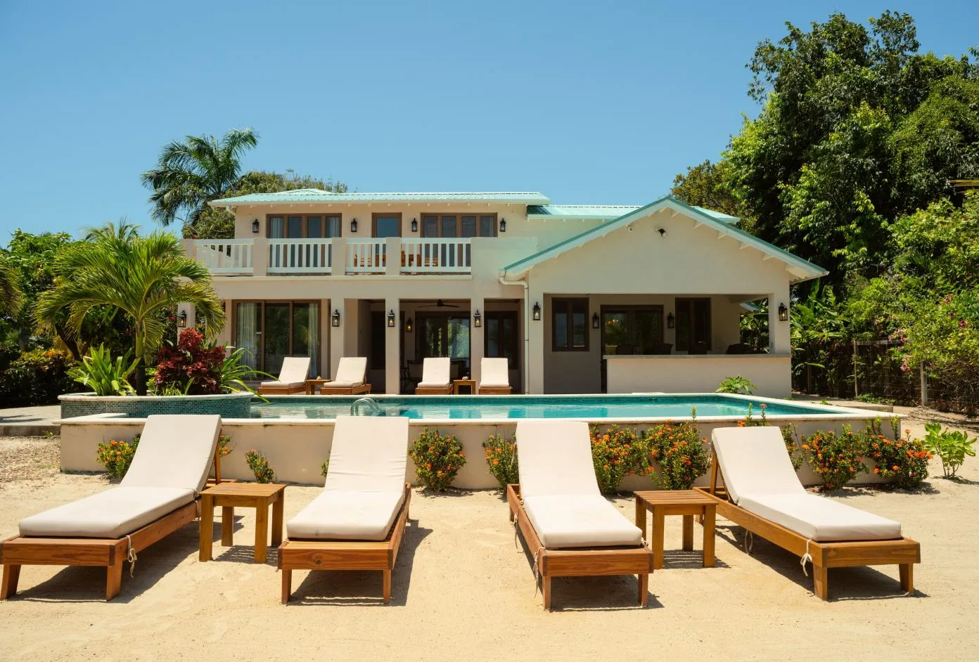 A house with a covered patio overlooks a swimming pool and outdoor seating.