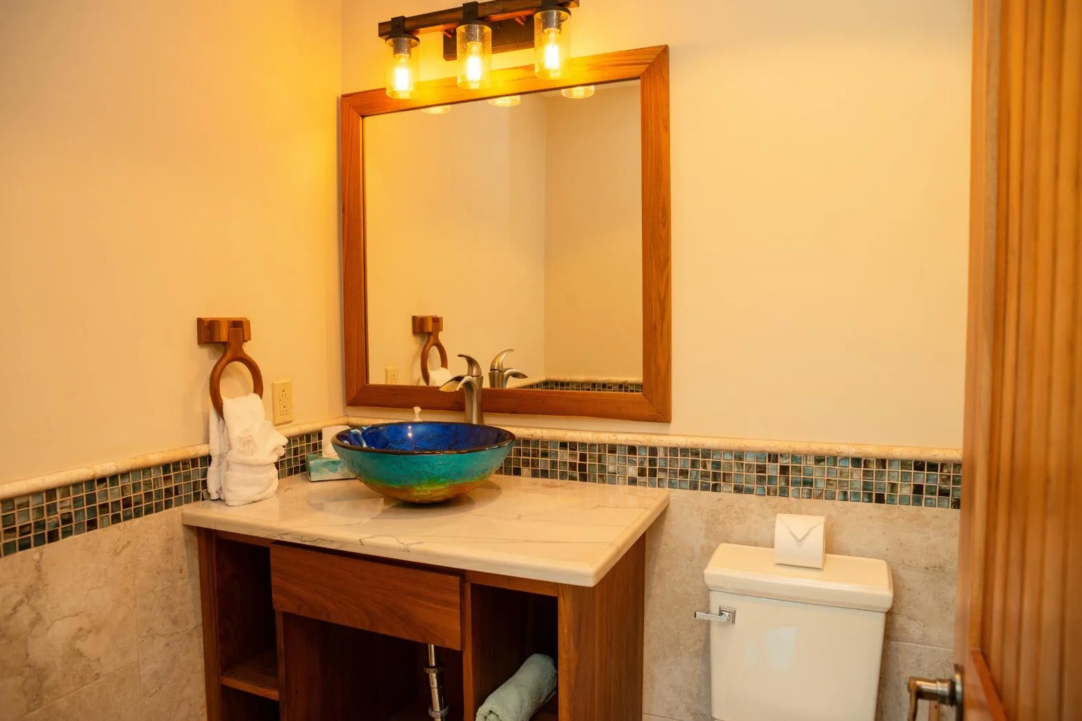 A bathroom vanity with a vessel sink, mirror, and toilet.