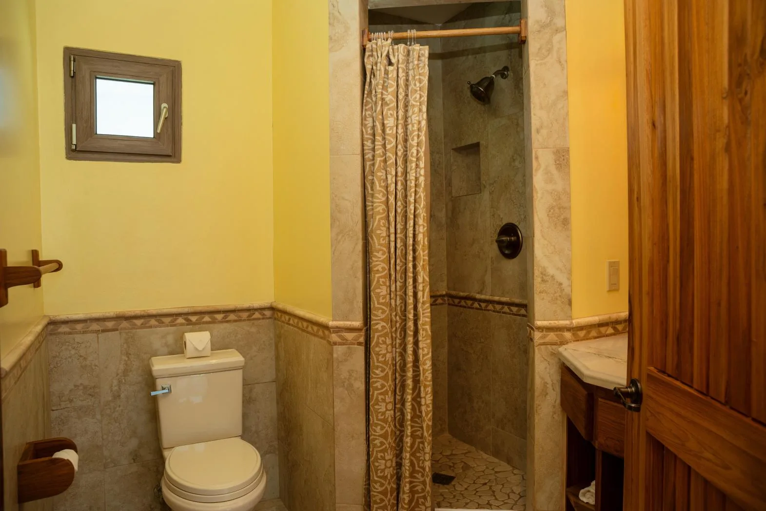 A bathroom with a toilet and a curtained shower.