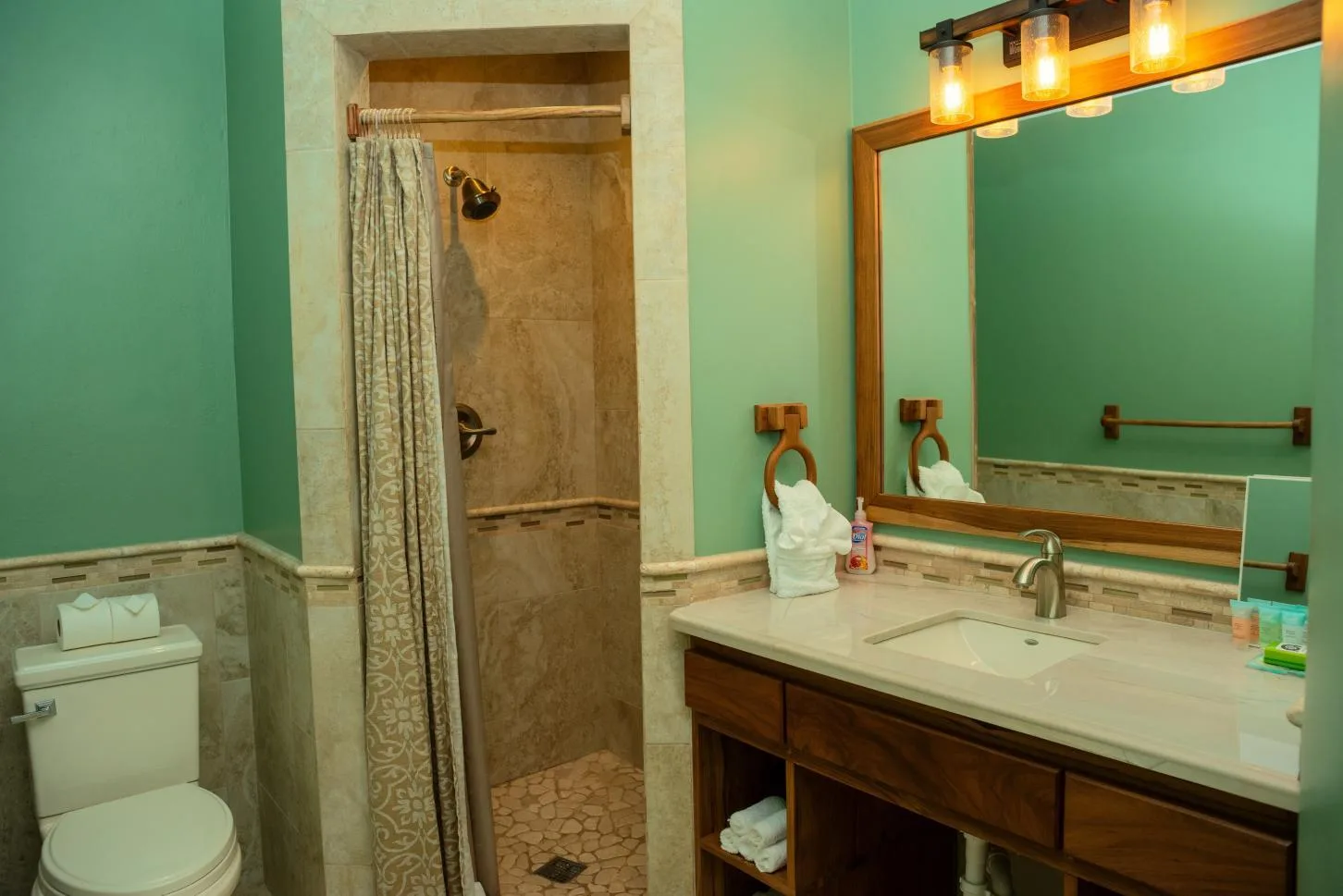 A bathroom with a shower, toilet, and long vanity beneath a mirror.
