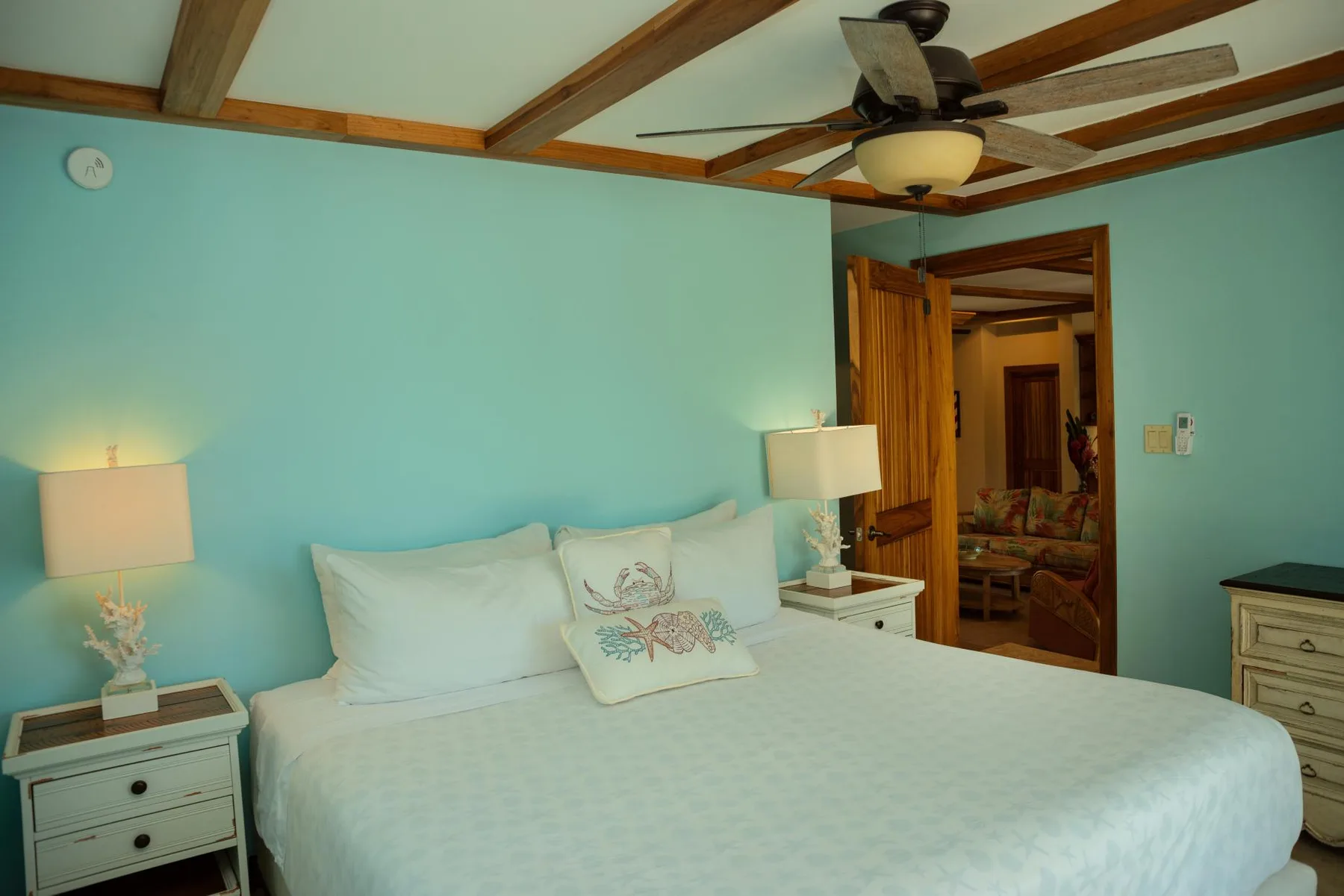 A bedroom with a neatly made bed, bedside tables, and an open doorway.
