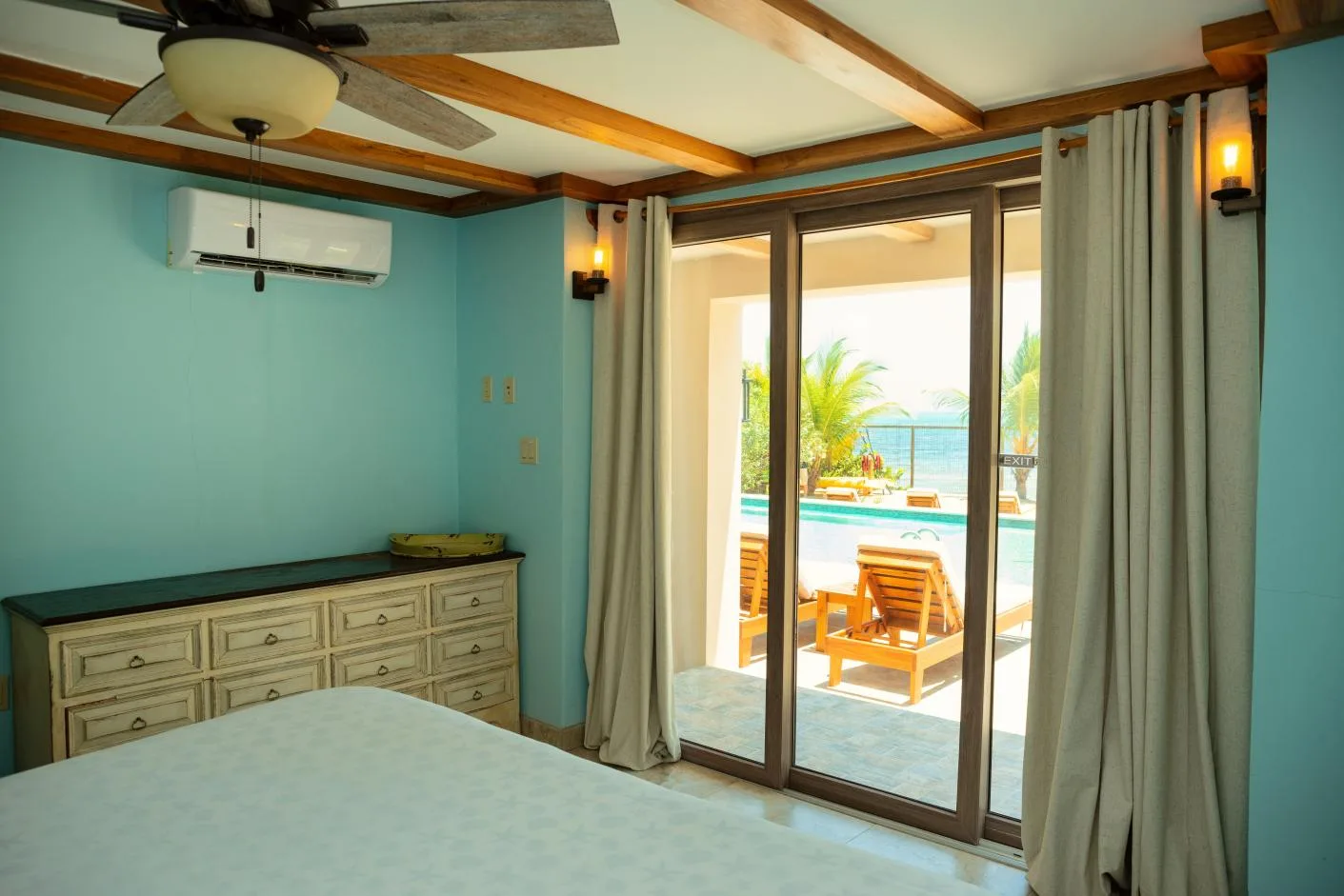 A bedroom with sliding glass doors opening onto a patio beside a pool.
