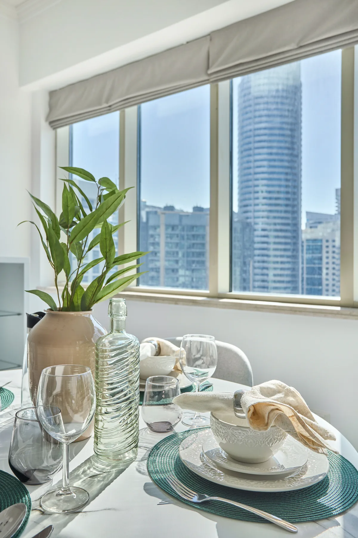 Una mesa de comedor junto a grandes ventanas da a edificios cercanos.