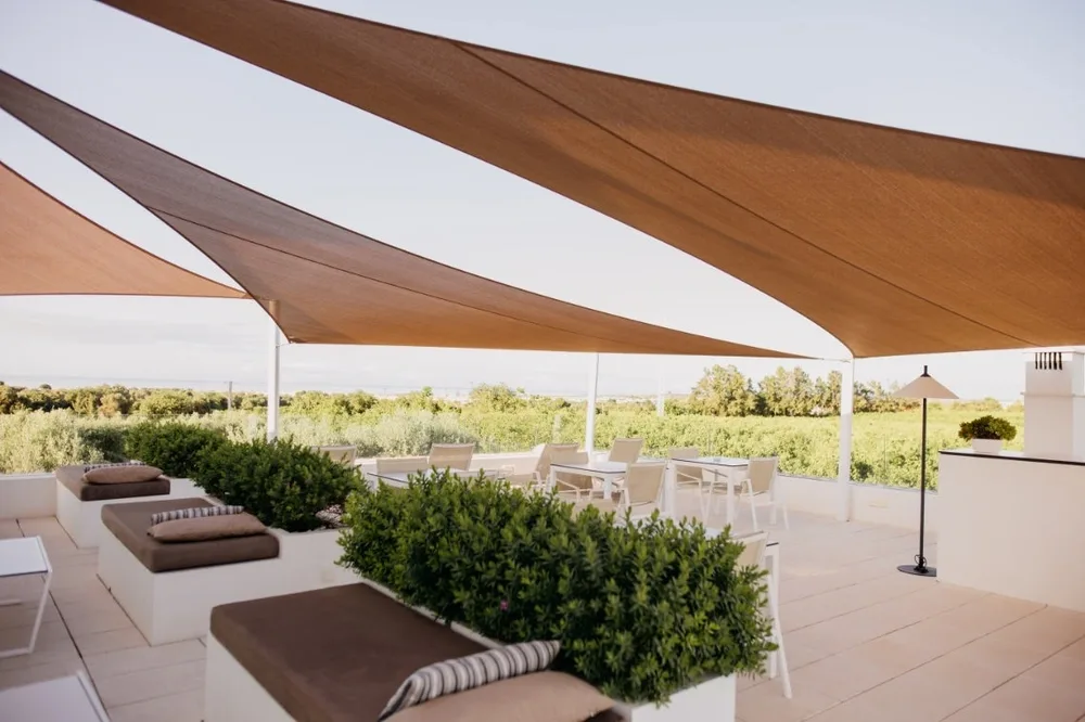 Representative hotel space: Outdoor patio seating sits beneath a fabric canopy, overlooking green landscaping.