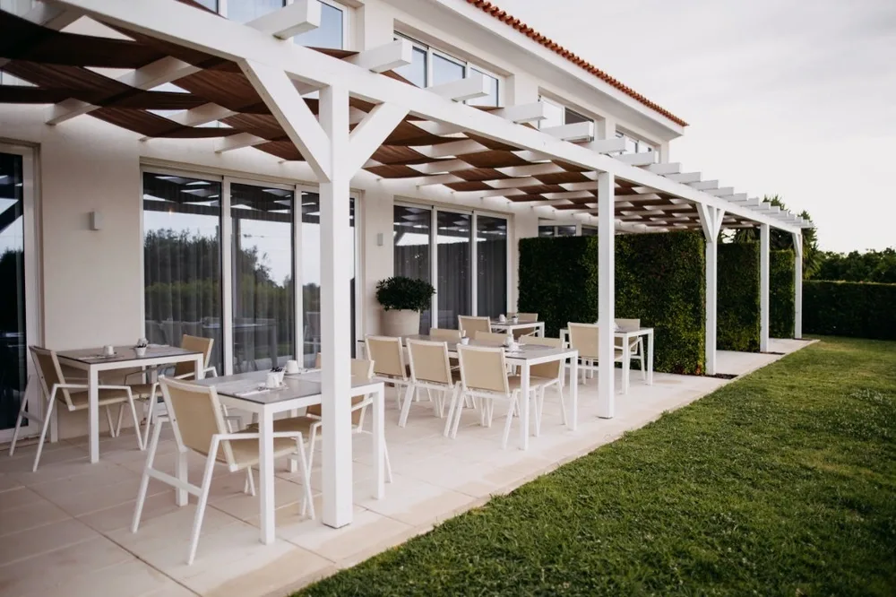 Representative hotel space: An outdoor dining patio with tables beneath a white pergola.