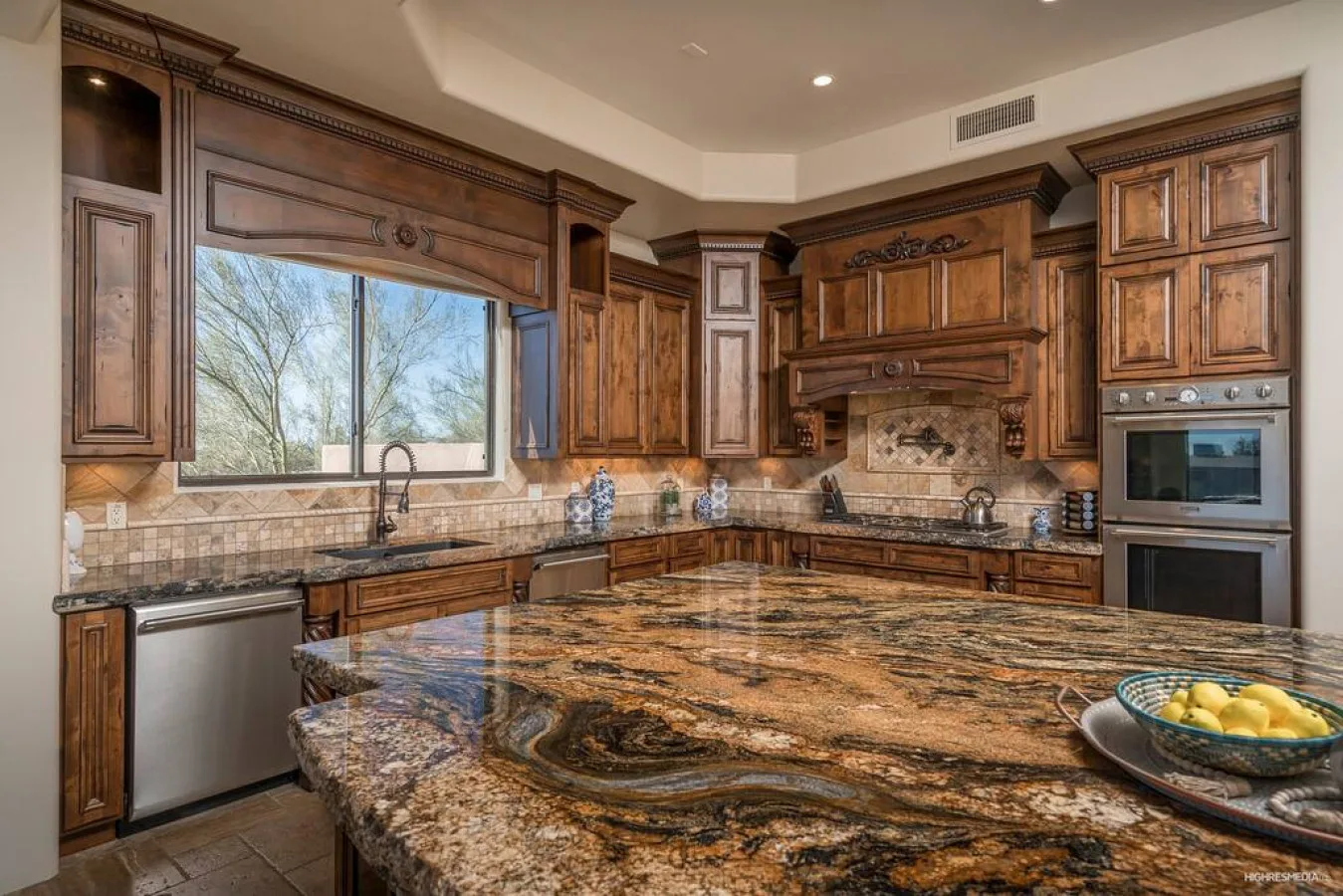A spacious kitchen with dark wood cabinetry and a large patterned island.