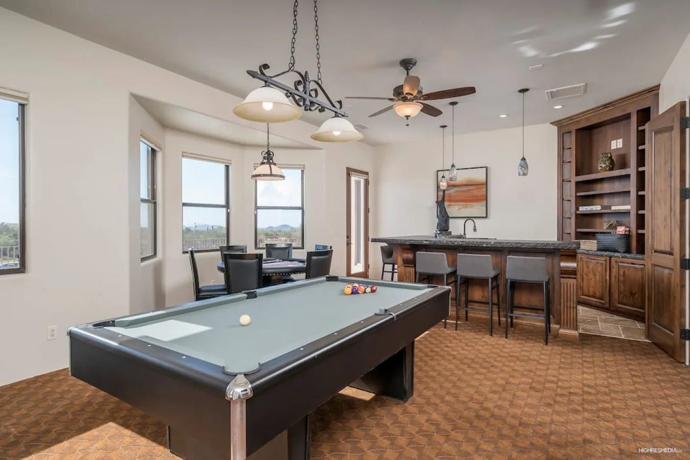 A game room features a pool table, dining table, and bar seating.
