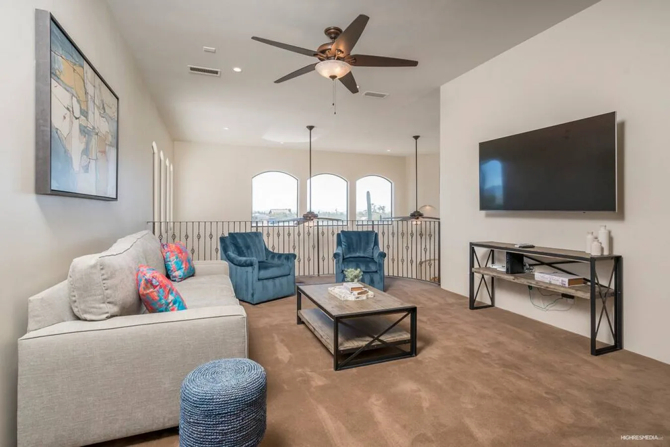 A living room with seating, a television, and windows overlooking a railing.