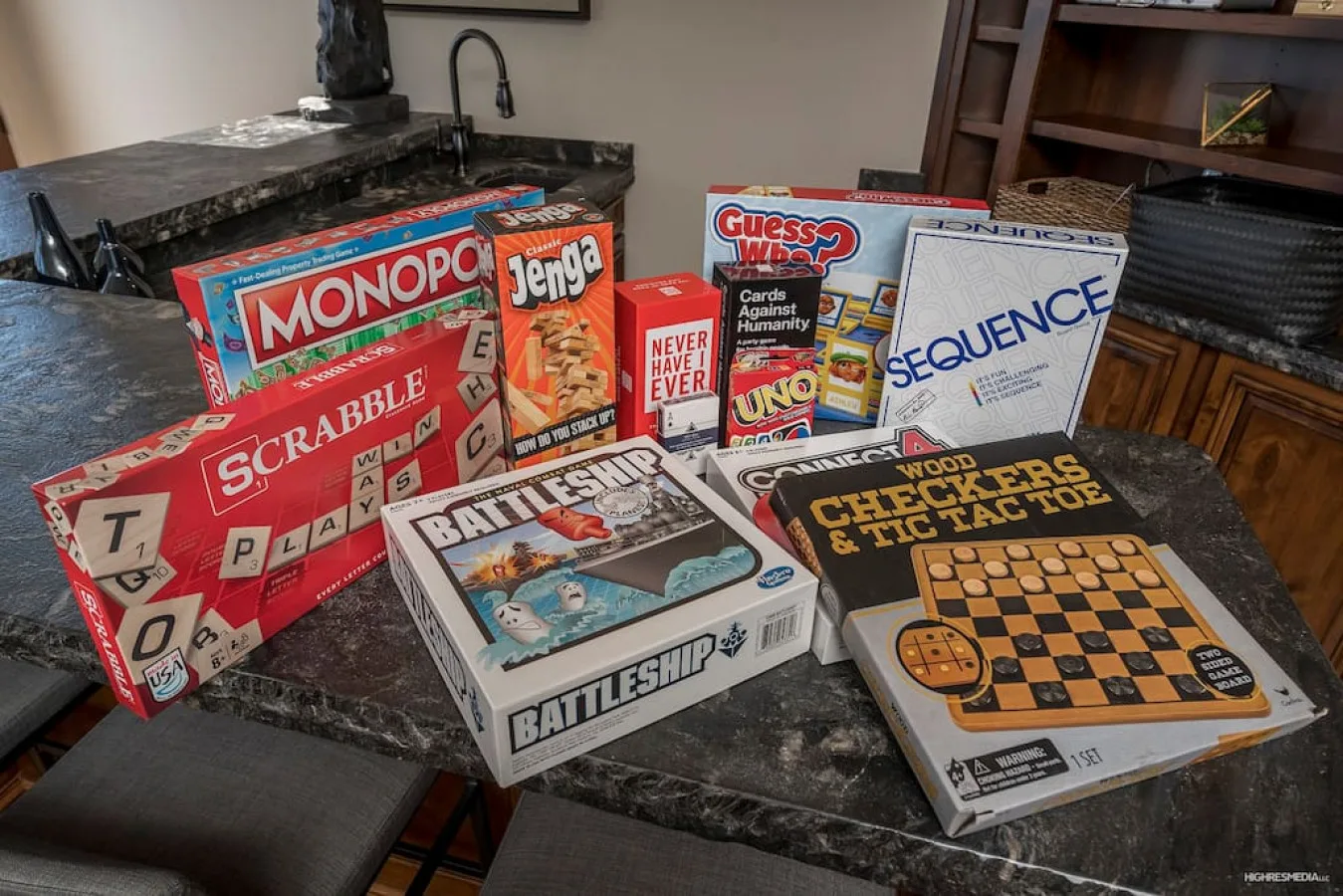 Board games are arranged across a dark kitchen island, including Monopoly and chess.