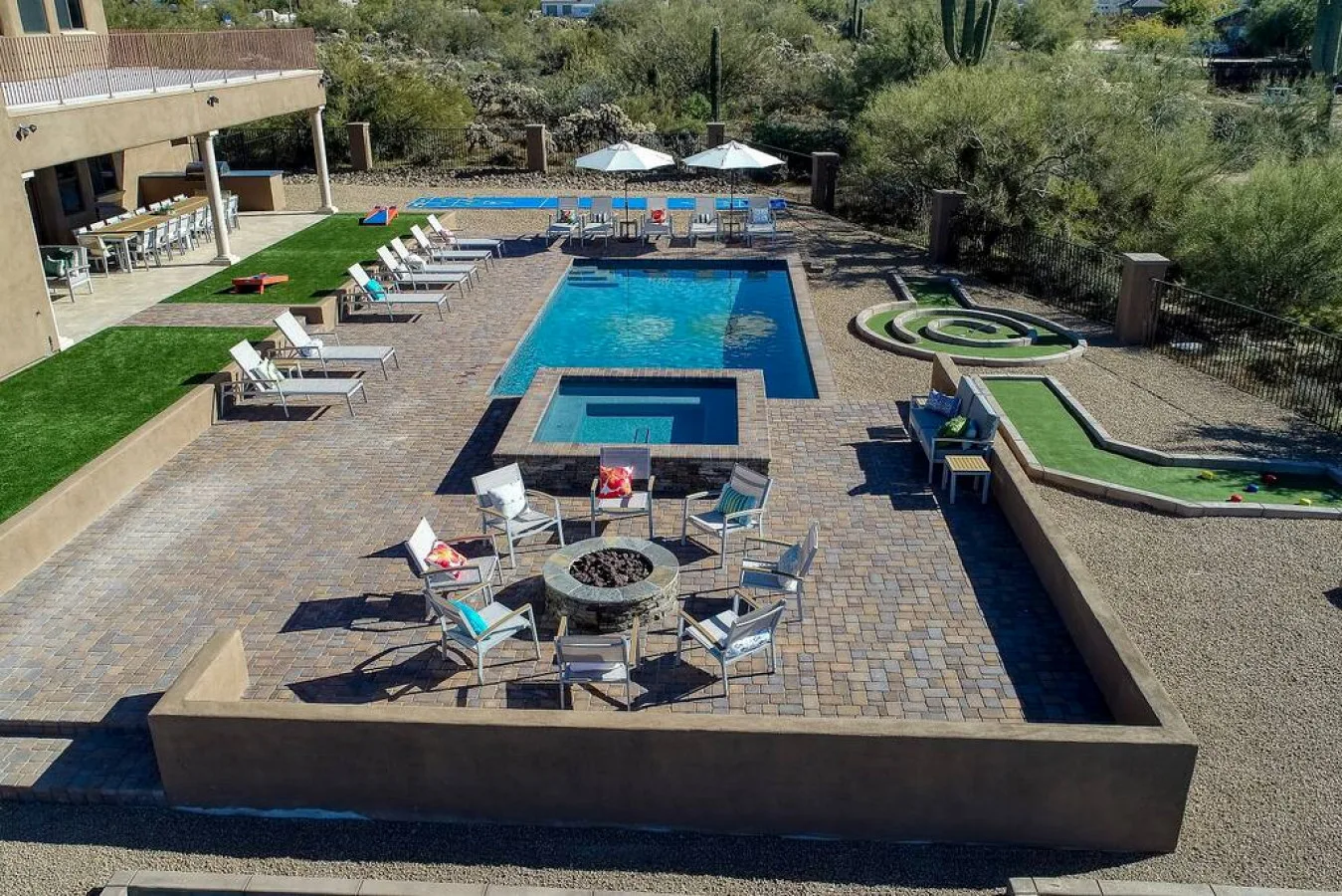 An outdoor pool area with surrounding paved seating and landscaped grounds.