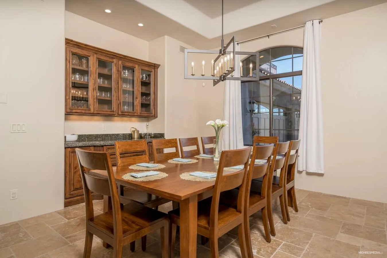 A dining room with a wooden table and chairs beneath a hanging light.