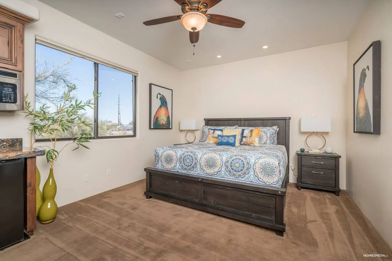 A bedroom with a bed, bedside tables, and a ceiling fan.