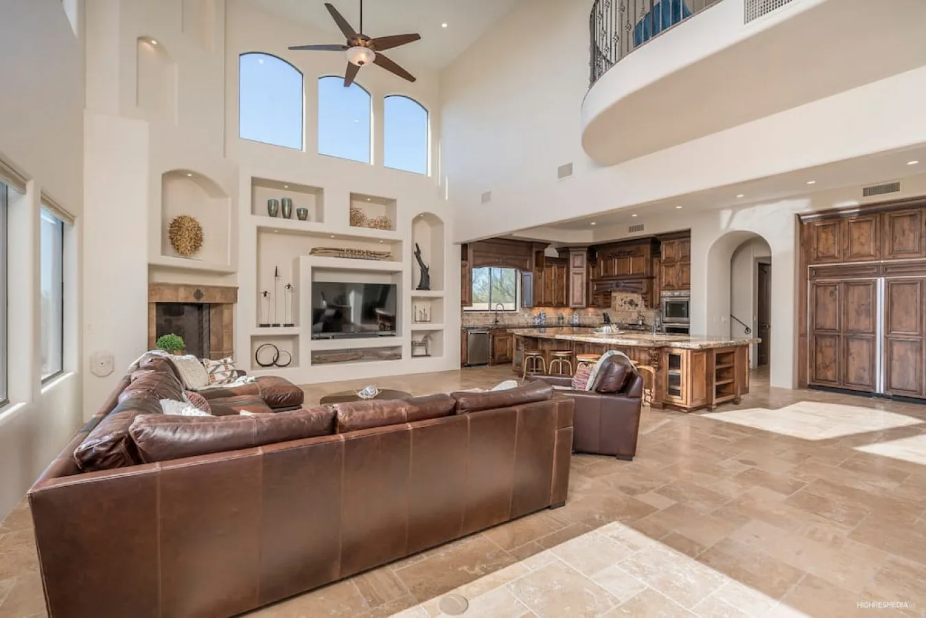 A spacious living room opens into a kitchen, with high windows above the seating area.