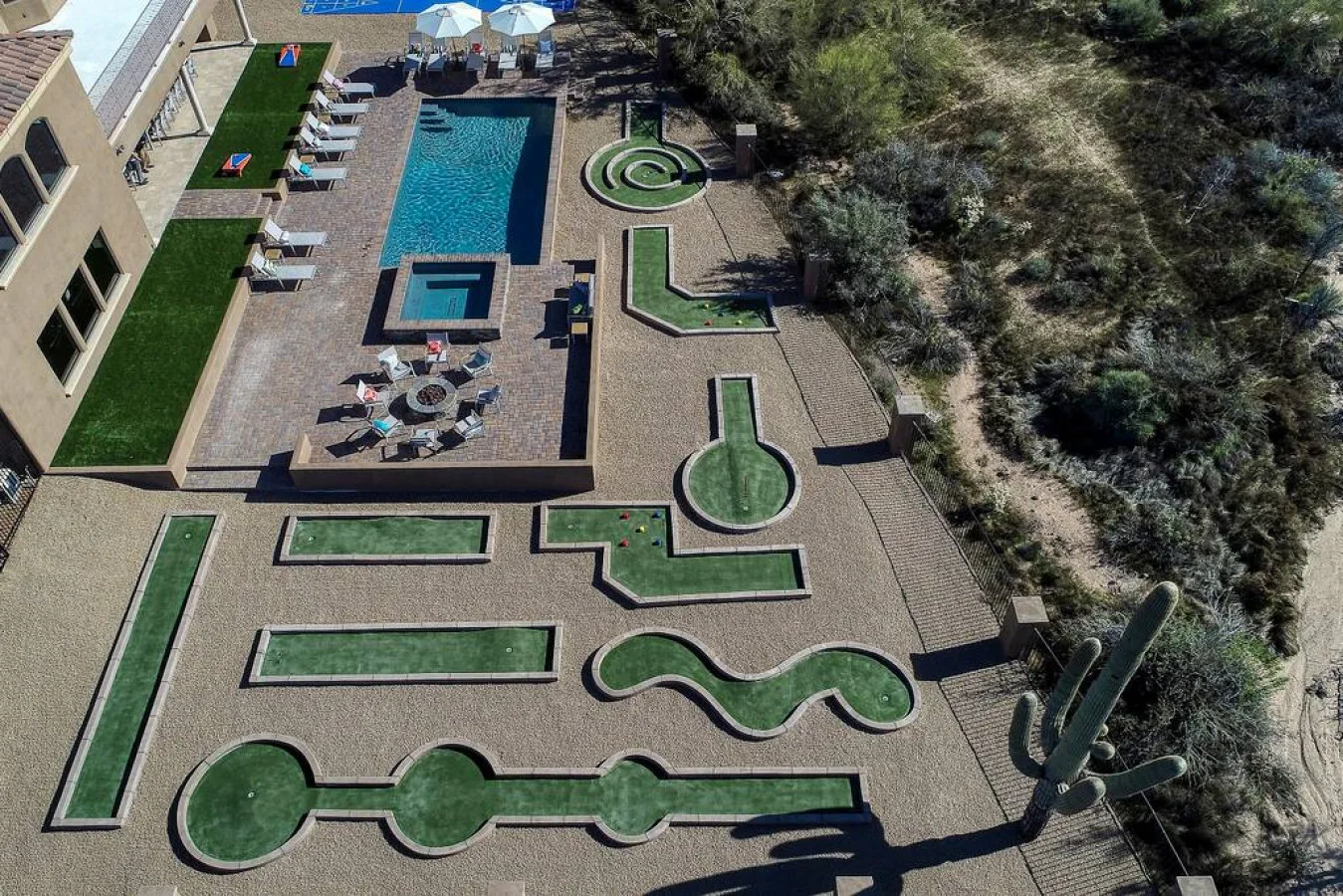 An aerial view of a landscaped courtyard with a swimming pool and winding green spaces.