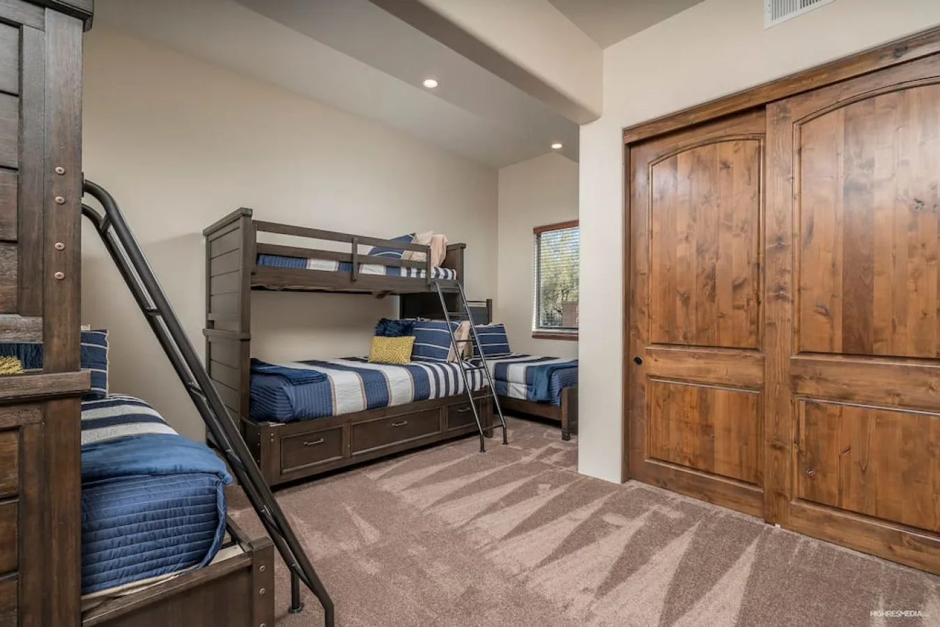 A bedroom with bunk beds and blue bedding beside wooden closet doors.